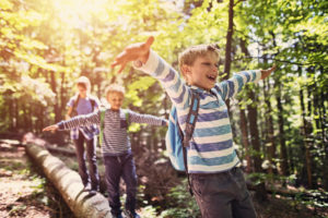 Little hikers walking on a tree trunk  in forest